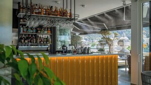 A bar area with a yellow counter, shelves with bottles, and hanging glasses. - Monograph Freedom Square (Tbilisi)