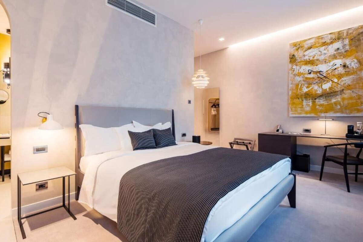Ein modernes Hotelzimmer mit Bett, Schreibtisch und einem großen abstrakten Gemälde.