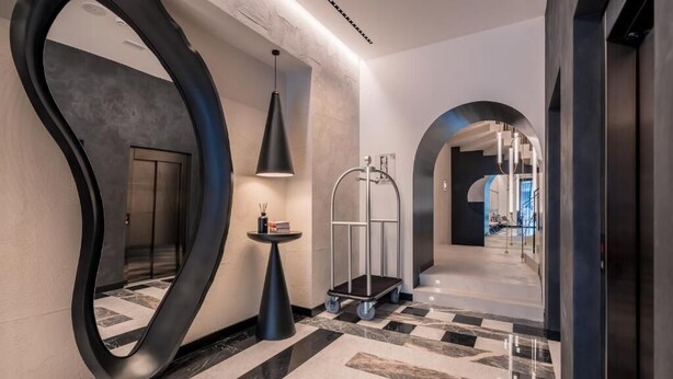 A modern hallway with a large mirror, a small table with a lamp, and a cart. - Monograph Freedom Square (Tbilisi)