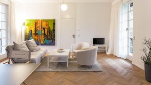 Ein modernes Wohnzimmer mit Sofa, Sessel, Couchtisch und einem Bild an der Wand.