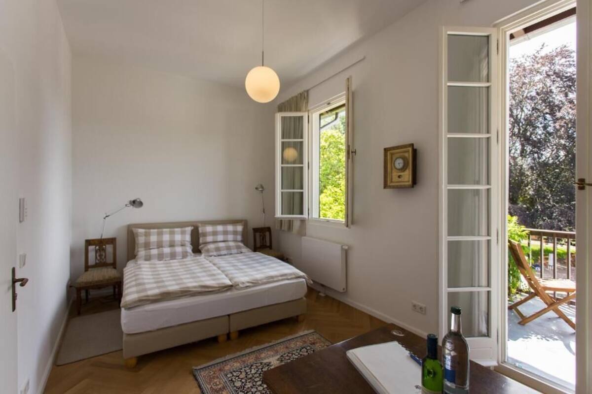 Ein Schlafzimmer mit Bett, Stuhl, Tisch, Fenster und Tür.