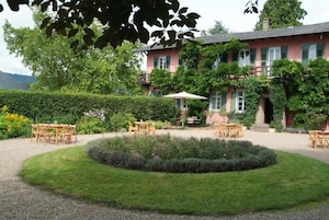 A pink building with a garden, outdoor seating, and a circular lawn feature.