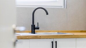 A modern kitchen with a black faucet, white cabinets, and a wooden countertop. - Apartment 2 (Right) (Mössingen)