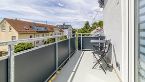 A balcony with a metal railing, a table, and two chairs. - Apartment 2 (Right) (Mössingen)