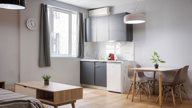 Eine moderne Küche mit grauen Schränken, einem weißen Geschirrspüler und einer Marmor-Spritzschutzwand.