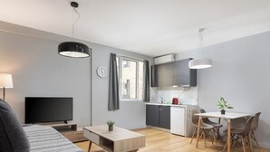 Eine moderne Wohnung mit Wohnbereich, einem Esstisch mit Stühlen, einer Küche und einem Fernseher.