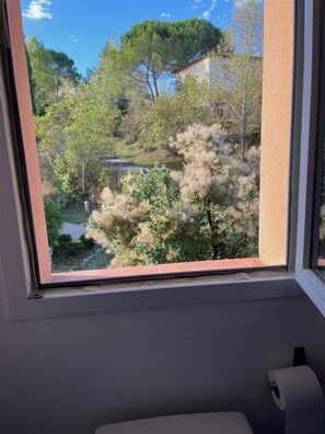 A window with a view of trees and a building. - House le Rouret (Grospierres)