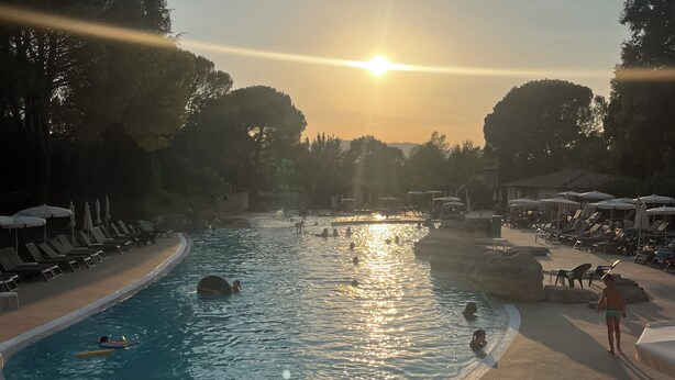 A pool area with sunlit water, lounge chairs, and umbrellas. - House le Rouret (Grospierres)