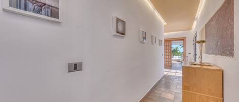 A hallway with a wooden cabinet, a window with a view, and a door leading to an outdoor area.