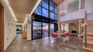 A spacious interior with a large glass door leading to an outdoor area, a dining area with red chairs, and a fireplace. - Villa El Erizo • Pool • LVH (Nazaret)