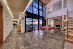 A spacious interior with a large glass door leading to an outdoor area, a dining area with red chairs, and a fireplace. - Villa El Erizo • Pool • LVH (Nazaret)