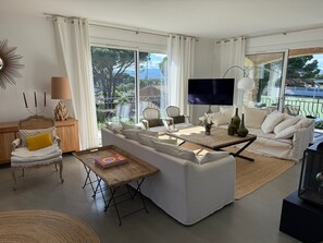 A modern living room with a sofa, coffee table, and a television. - Saint Tropez, private pool, 2 parking spaces.  Quiet, 10-minute walk to beach and town. (Saint-Tropez)