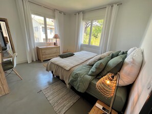 A bedroom with a bed, bedside table, lamp, and a view of the outside. - Saint Tropez, private pool, 2 parking spaces.  Quiet, 10-minute walk to beach and town. (Saint-Tropez)