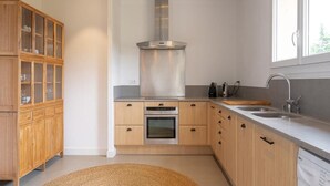 Eine moderne Küche mit Holzschränken, einer Edelstahl-Dunstabzugshaube und einem eingebauten Backofen.