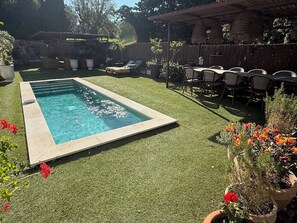 A rectangular pool with a tiled edge, surrounded by artificial grass, and a patio area with chairs and tables. - Saint Tropez, private pool, 2 parking spaces.  Quiet, 10-minute walk to beach and town. (Saint-Tropez)
