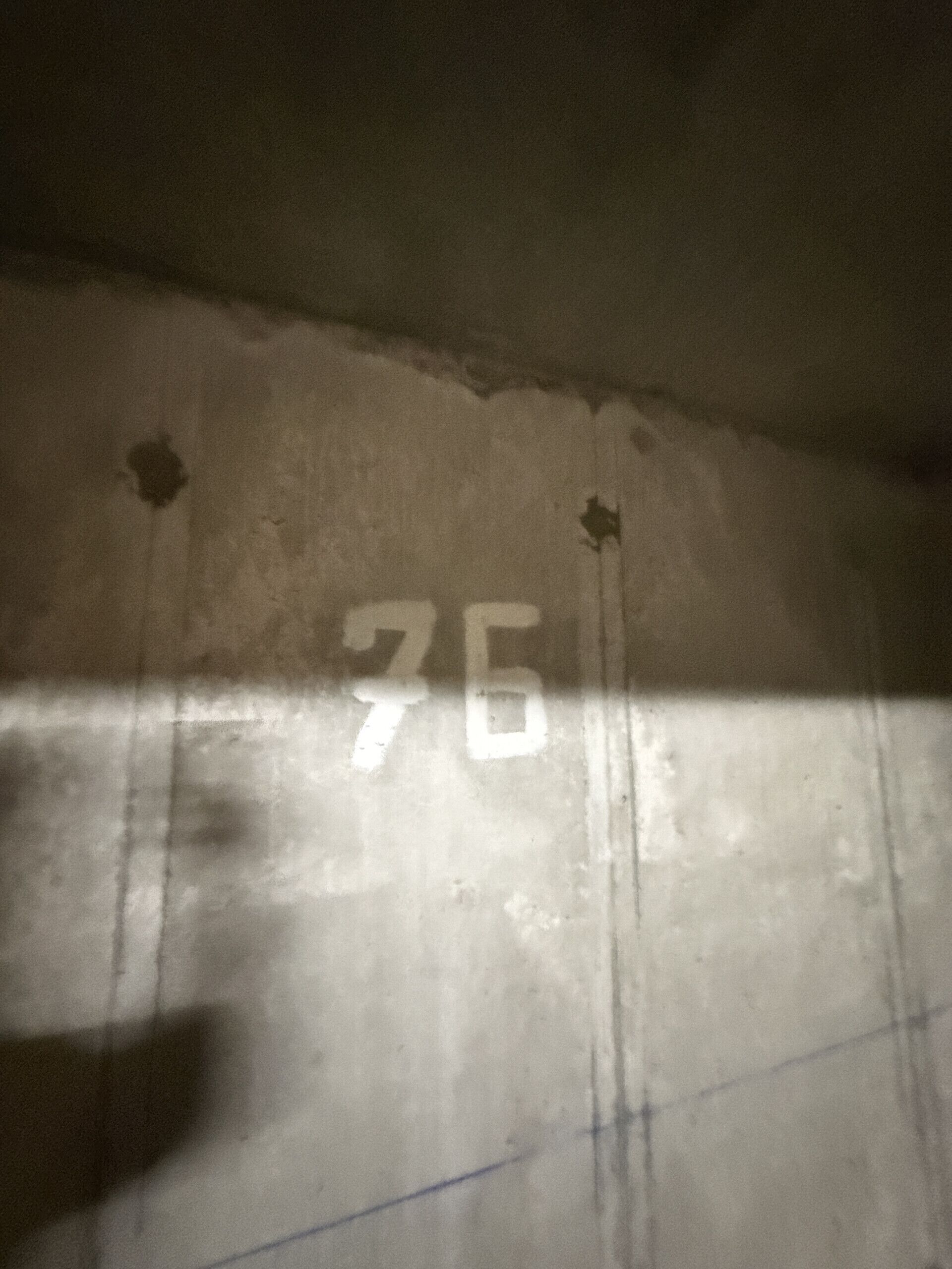 A wall with the number '76' and some marks.