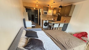Een knus verblijf met een bed, een kleine keuken en een wasmachine.