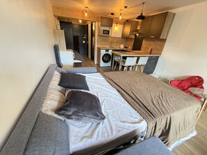 Ein kleines Zimmer mit einem Bett, einer Küchenzeile und einer Waschmaschine.