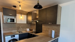 Een moderne keuken met een houten aanrechtblad, inbouwapparatuur en een bar met twee stoelen.