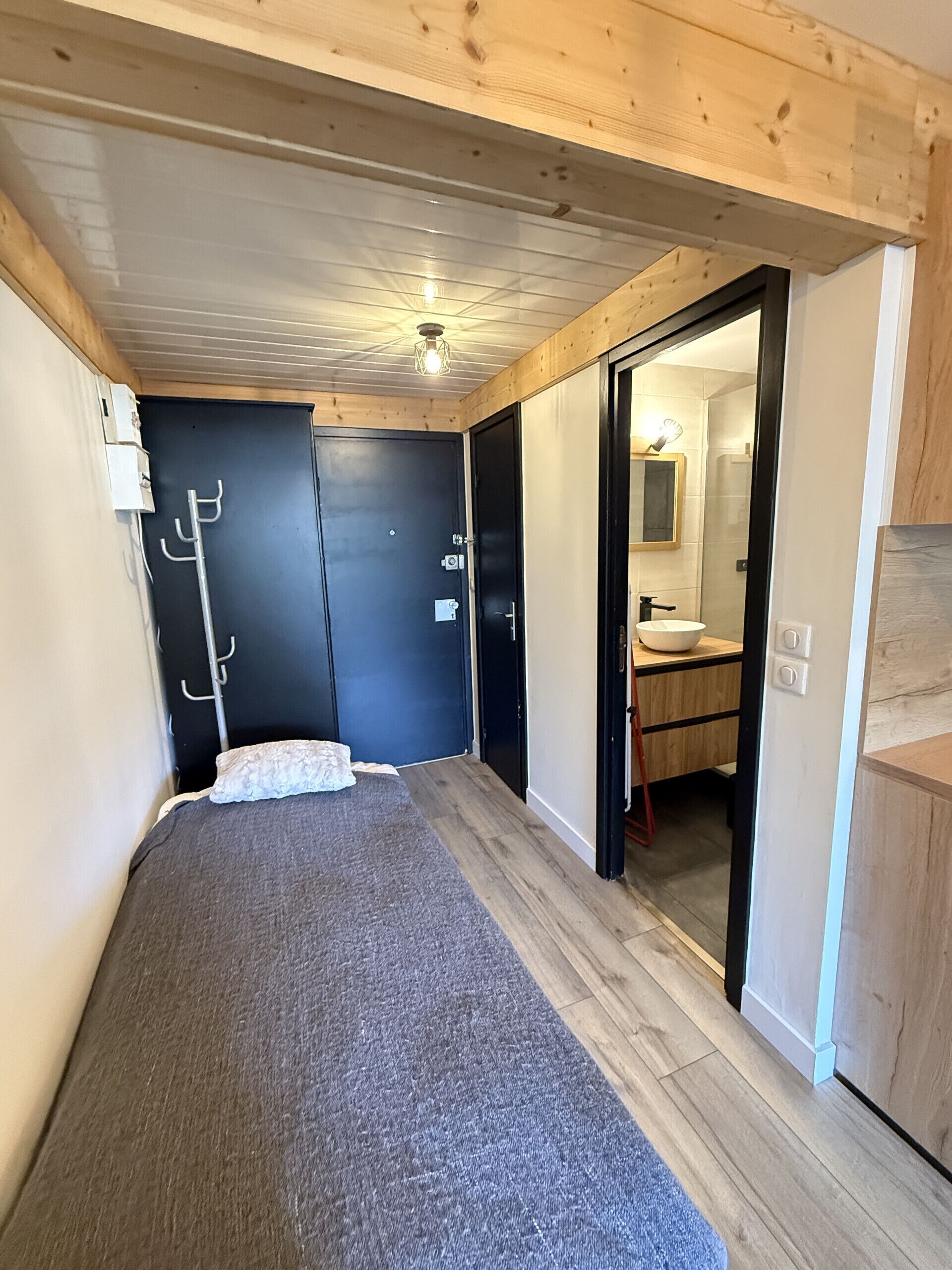 A bedroom with a bed, a wardrobe, a mirror, and a bathroom visible through an open door.