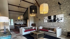 En rummelig opholdsstue med en stenvæg, et moderne sofasæt, et sofabord og hængende pendellamper.