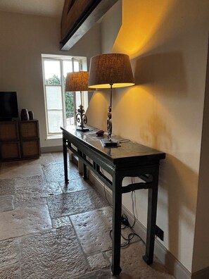 A room with a stone floor, a wooden bench with lamps, a television, and a window with a view. - Charming apartment-comfort and elegance-St Rémy De Provence-5 mn from town center (Saint-Rémy-de-Provence)