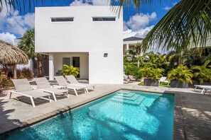 A modern building with a pool, lounge chairs, and tropical plants. - Luxury 5 star Villa with private pool 600 m from Jan Thiel Beach (Jan Thiel)
