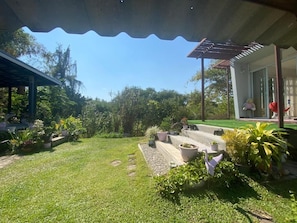 Un jardín bien cuidado con césped, plantas en macetas y una estructura de pérgola.
