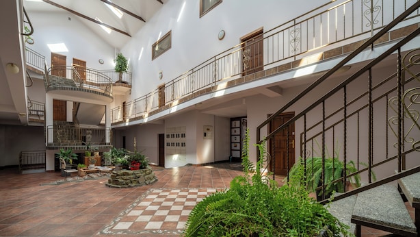 Un atrium ample amb un paviment a escacs, una escala central i diversos nivells amb balcons.