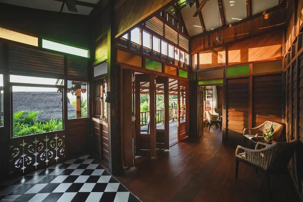A spacious interior with a checkered floor, wooden walls, and large windows offering a view of greenery.