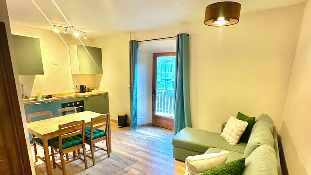 Ett modernt vardagsrum med en grön soffa, ett matbord i trä och stolar.