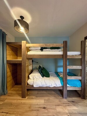 A bunk bed room with a wooden floor, a ceiling light, and a wall-mounted outlet. - The Little Alpine Refuge - Studio sleeping 4 (Saint-Jean-d'Aulps)