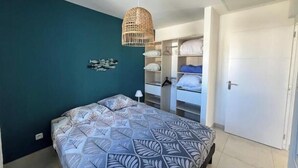 Um quarto com cama, luminária pendente, armário e porta.