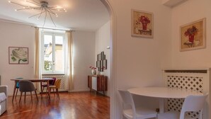 A dining area with a table and chairs, a sofa, and a window with curtains.