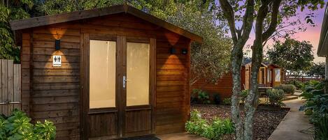 A wooden cabin with a porch, a sign indicating a restroom, and a pathway leading to it.