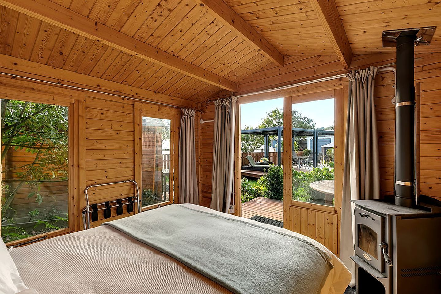 A wooden cabin with a bed, a fireplace, and a view of the outdoors.