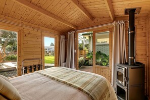 A wooden cabin with a bed, a fireplace, and a patio area.
