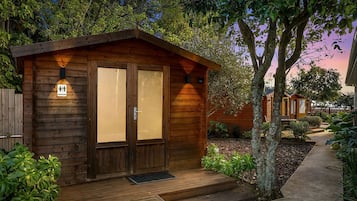 A wooden cabin with a porch, a sign indicating a restroom, and a pathway leading to it.