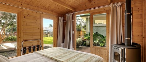 Una cabaña de madera con cama, chimenea y un patio.