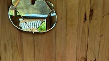 Ein Badezimmer aus Holz mit einem weißen Waschbecken, einem Spiegel und einer Toilette.