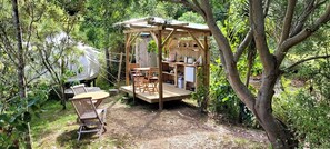 A wooden structure with a table and chairs, surrounded by trees.