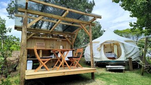 A wooden structure with a table and chairs, a tent, and a covered area with a roof. - Sunny Vineyard-View Glamping with Outdoor Kitchen near Oneroa, Waiheke Island (Isla Waiheke)