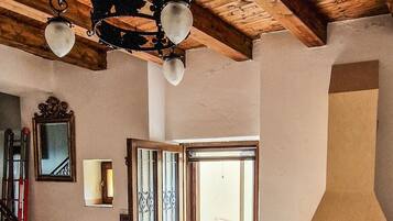 Un intérieur spacieux avec un plafond en bois, une cheminée, un escalier et une porte donnant sur l’extérieur.