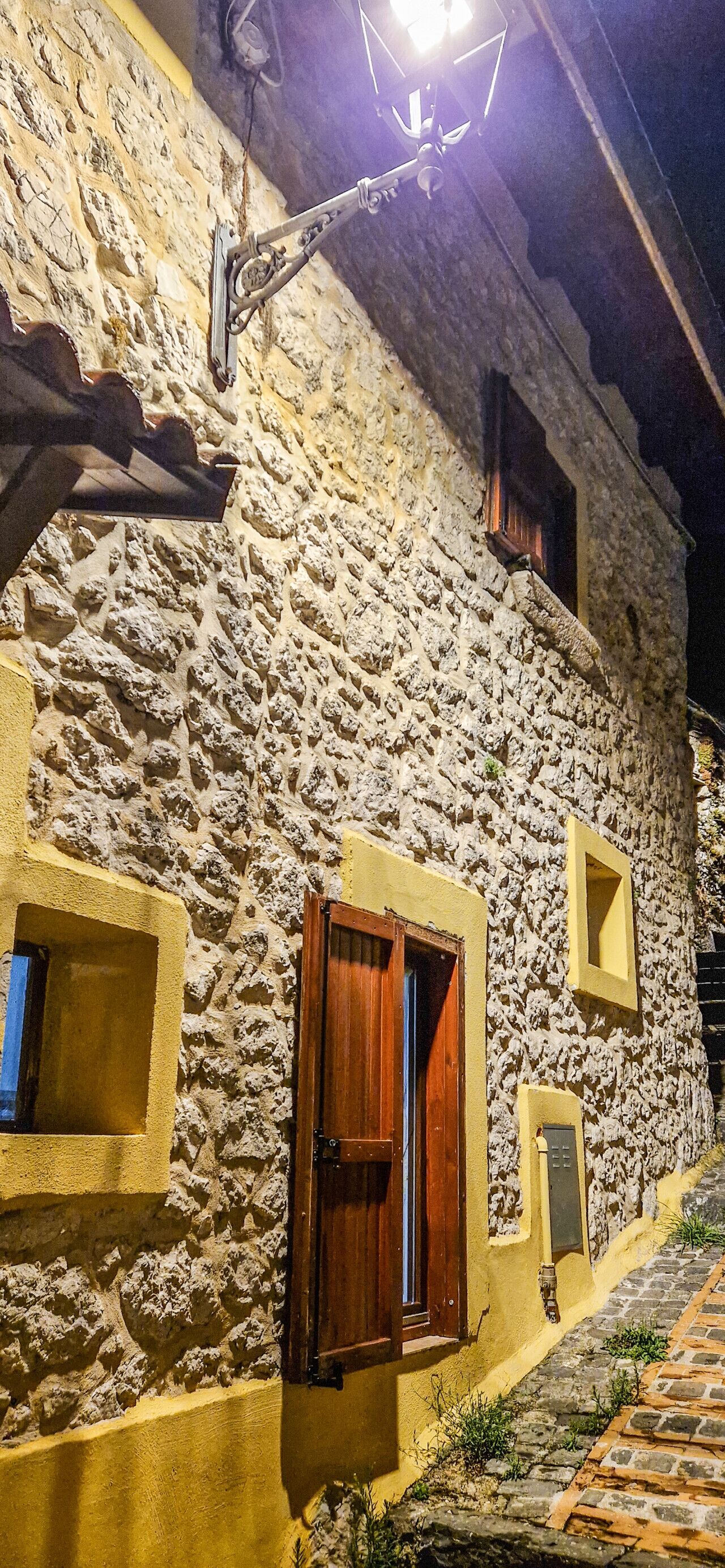 Un edificio in pietra con una facciata gialla, una porta in legno e una piccola finestra.