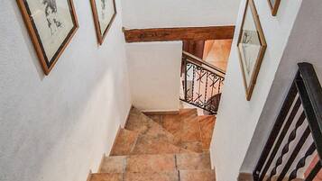 Un escalier avec des marches en pierre, des murs blancs et des tableaux encadrés.