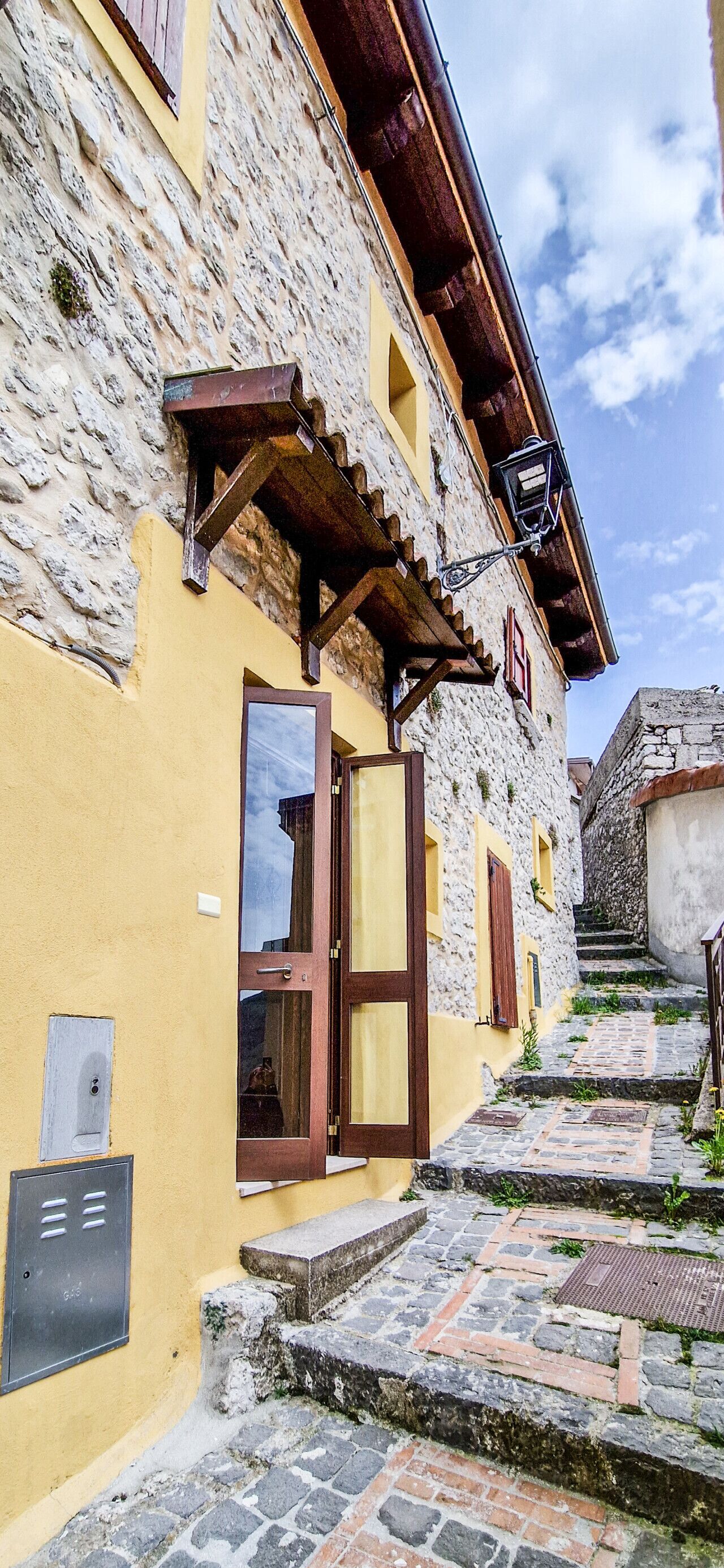 Un bâtiment en pierre avec une façade jaune, une porte en bois et une petite fenêtre.