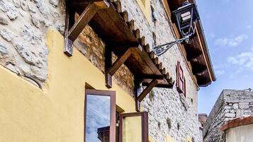 Un bâtiment en pierre avec une façade jaune, une porte en bois et une petite fenêtre.