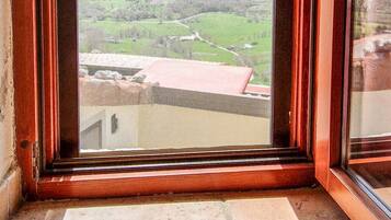Une fenêtre donnant sur un paysage montagneux et un bâtiment avec un toit rouge.