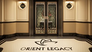Entrada de hotel con puertas dobles, placas numeradas y un logotipo en el suelo.