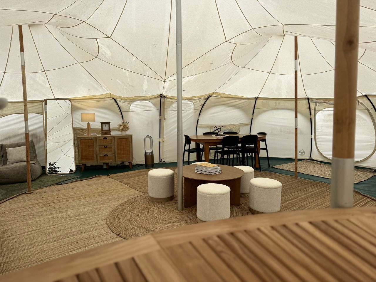 Een tentaccomodatie met een centrale tafel, zitplaatsen en een kast.